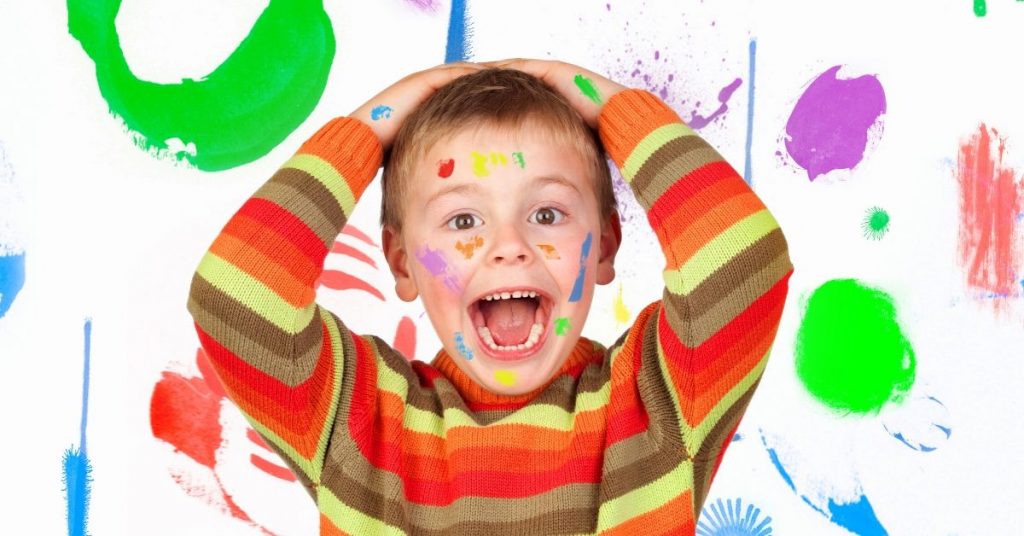 Niño con las manos en la cabeza y todo pintado alrededor